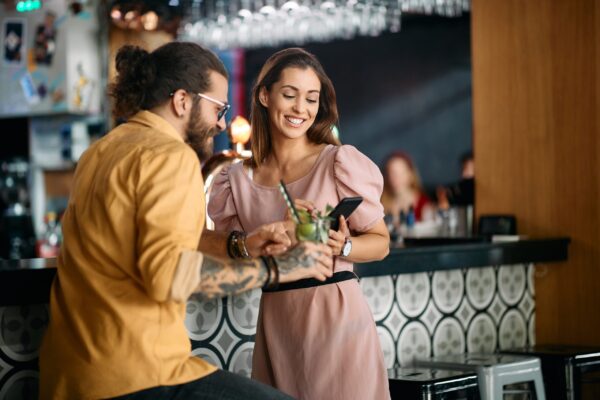 Happy,Woman,And,Her,Boyfriend,Using,Mobile,Phone,While,Dating